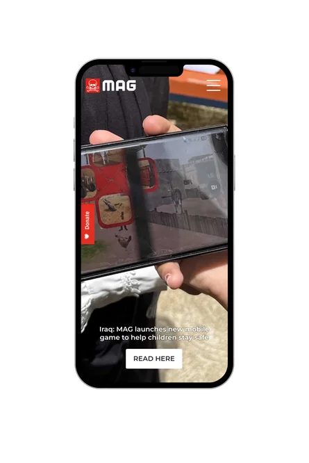 A phone showing the Mines Advisory Group homepage, with "Iraq: MAG launches new mobile game to help children stay safe" headline and a Read here button.
