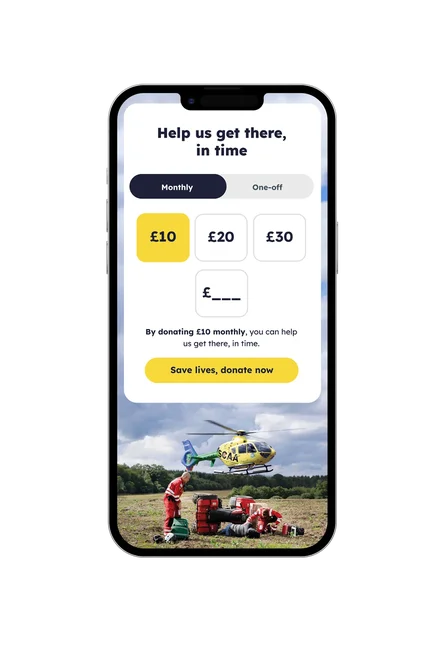 Mobile phone showing the SCAA donation page with monthly and one-off options, preset donation amounts, custom amount field, and a yellow ‘Save lives, donate now’ button above a photo of an air ambulance crew.