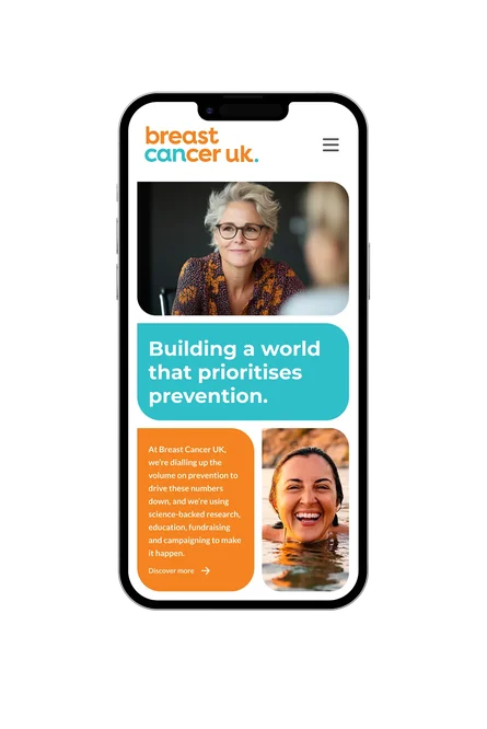 A mobile phone showing the Breast Cancer UK homepage featuring prevention messaging and images of smiling women.