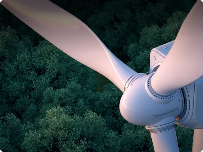 A close-up view of a wind turbine rotor and blades seen from above, with a dense forest canopy visible below.