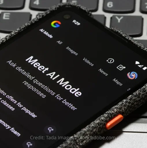 A smartphone screen displaying Google's AI Mode interface with the headline "Meet AI Mode" and example prompts, placed on top of a laptop keyboard.