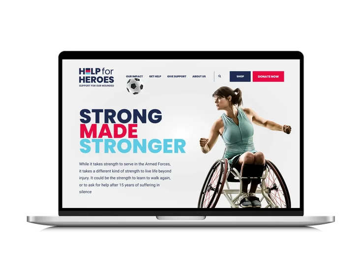 A laptop showing the Help for Heroes desktop homepage, with "Strong Made Stronger" headline, intro copy, a wheelchair athlete, and full site navigation.